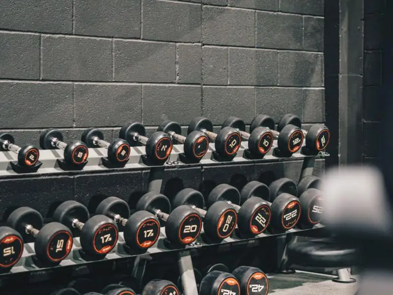 Racks of rubber dumbbells against a brick wall
